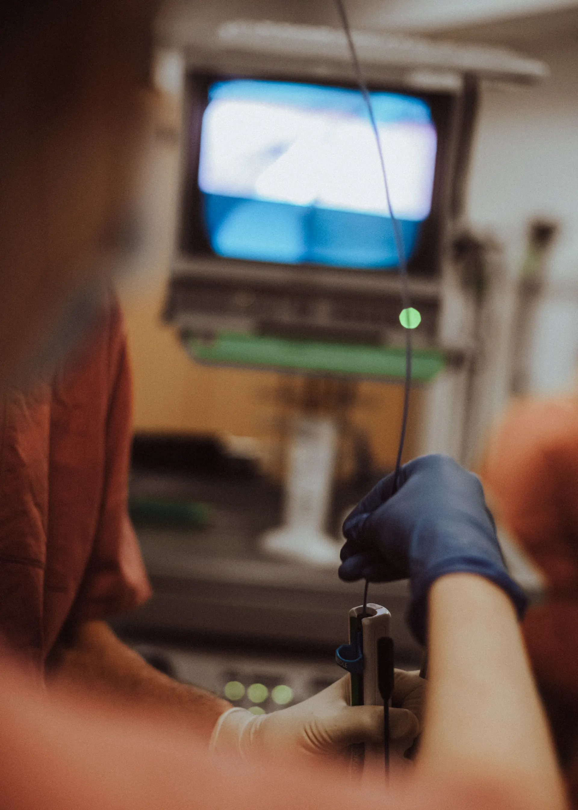 Hand bedient de endoscoop, op de achtergrond de monitor van de gastroscopie