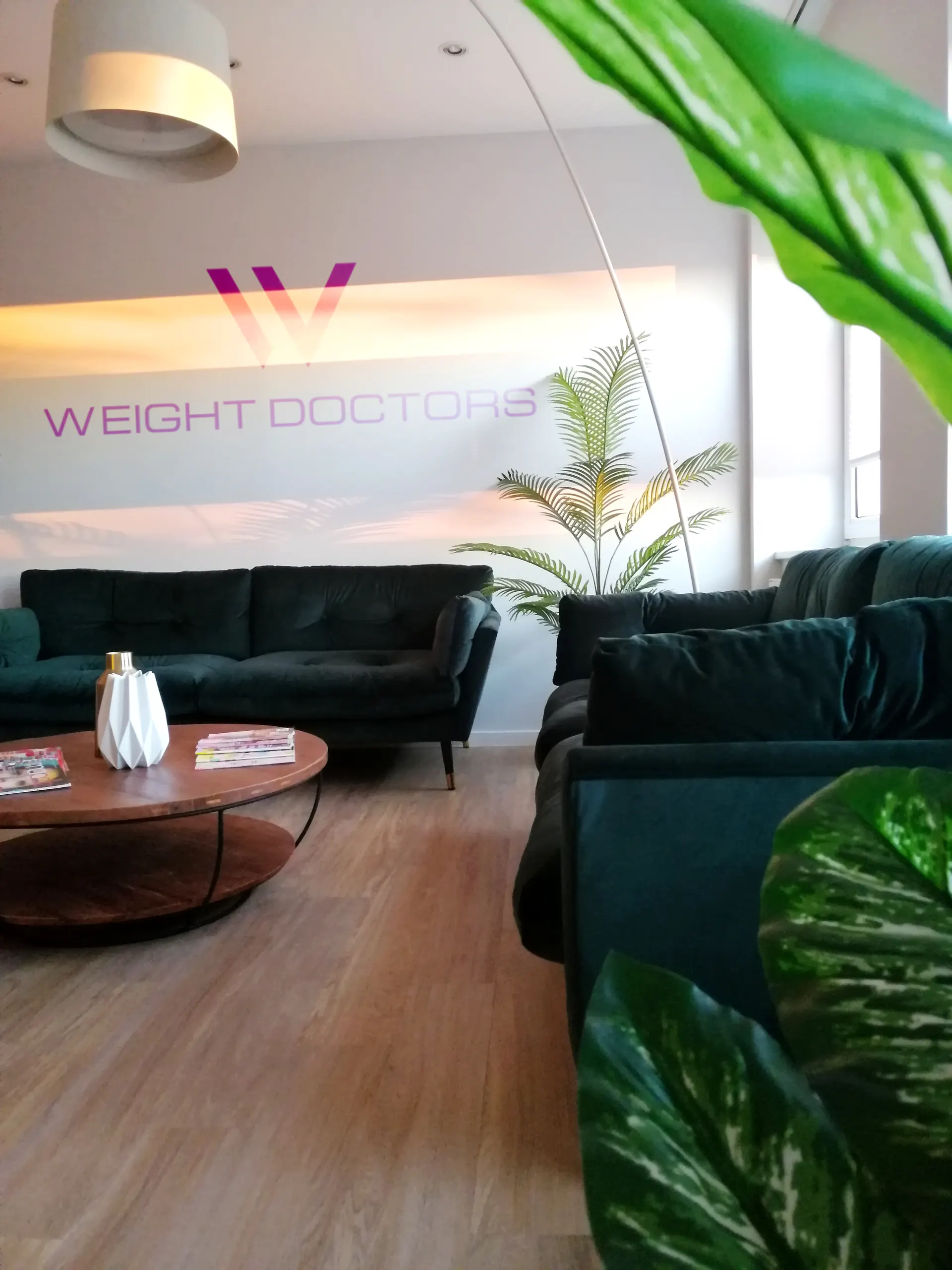 Lounge van Weight Doctors® met groene banken en de belettering op de muur