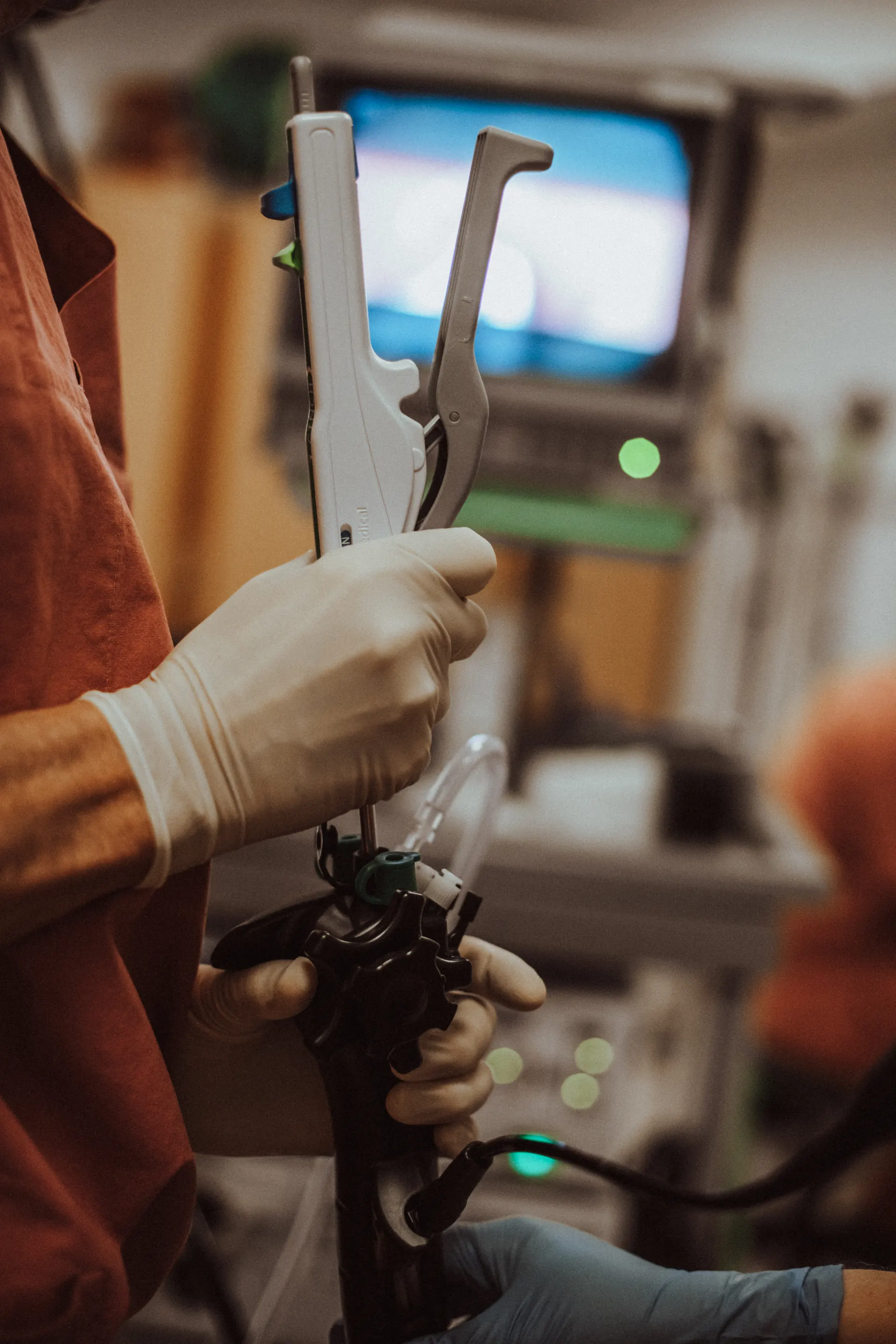 Endoscopic suturing instrument in the specialist’s hand, with the monitor in the background
