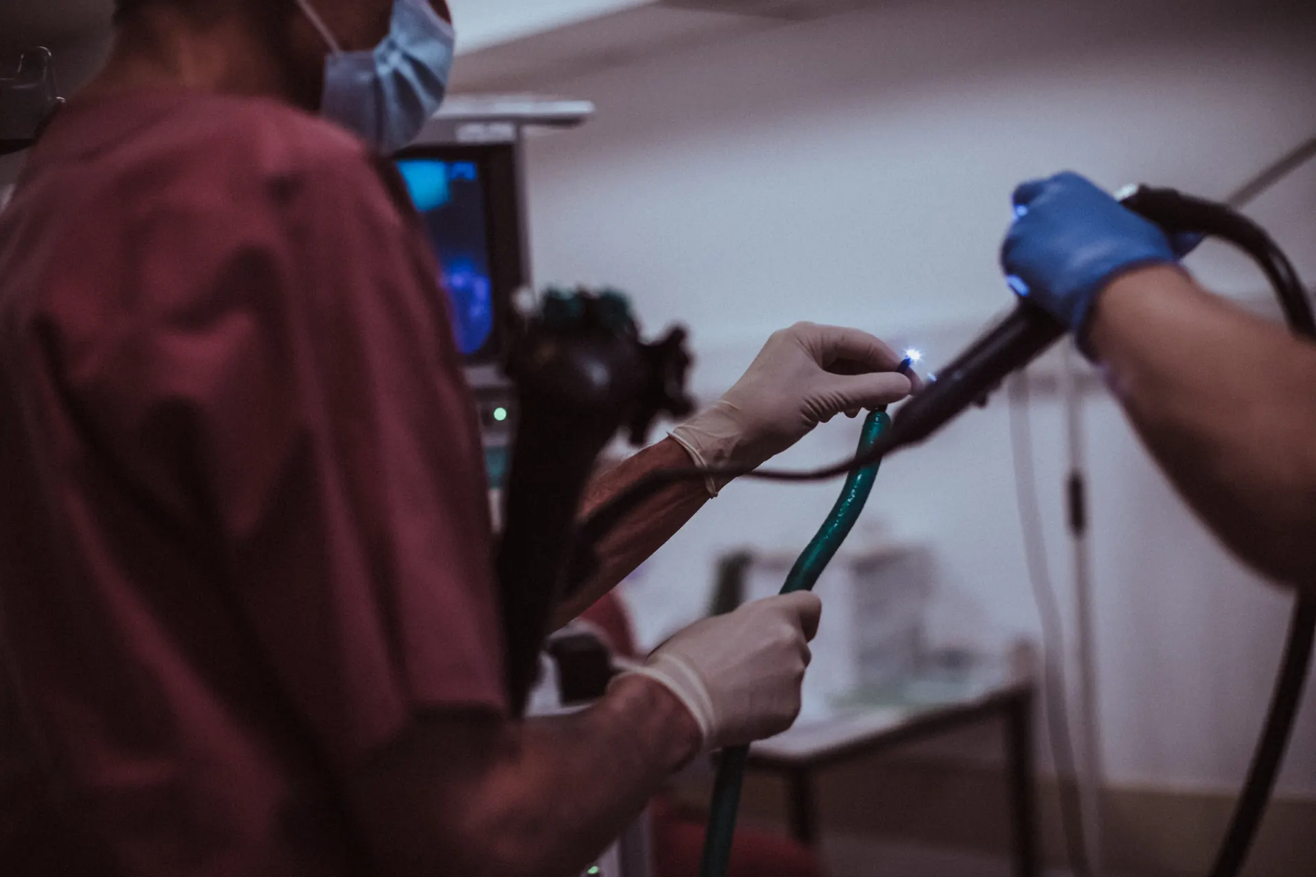 Hands guiding the gastroscope, the endoscopy monitor in the background