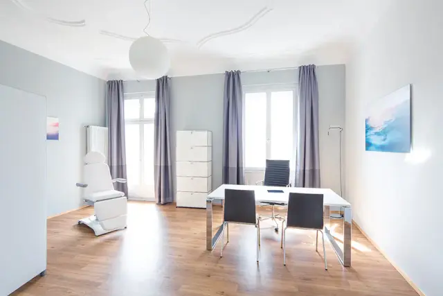 Salle de consultation lumineuse avec bureau et table d’examen chez Weight Doctors® à Francfort-sur-le-Main
